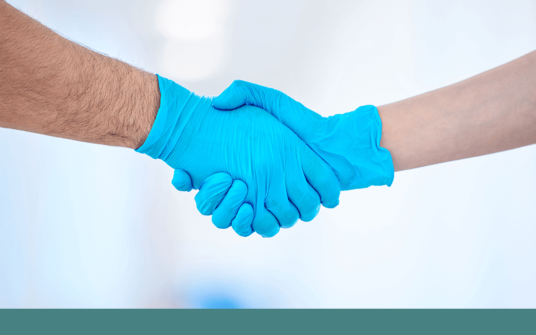 Photo of two people wearing surgical gloves shaking hands. Photo de deux personnes portant des gants chirurgicaux se serrant la main.