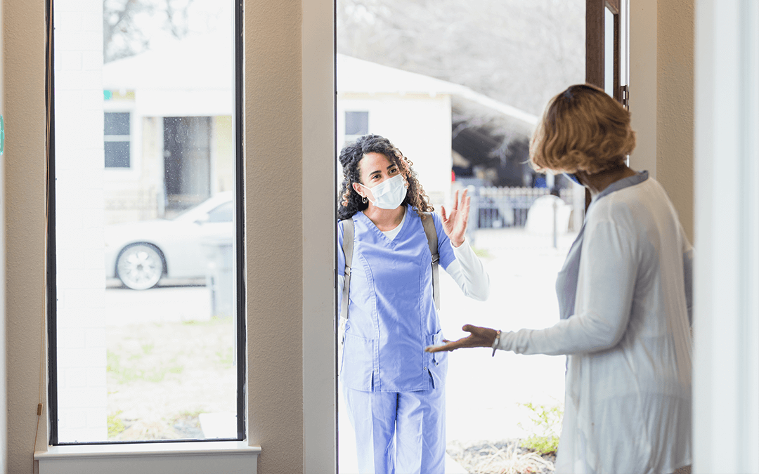 Nurse greeting a woman at the door. Infirmière saluant une femme à la porte de sa maison.