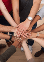Photo of a group of people putting their hands together. Une photo d'un groupe de personne tennant les mains.